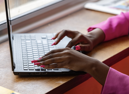 Woman with Long Pink Nails Typing on a Laptop